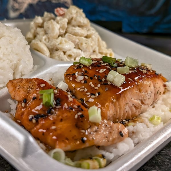 Hawaiian salmon plate lunch with rice, macaroni salad, and green onions in a white takeout container.